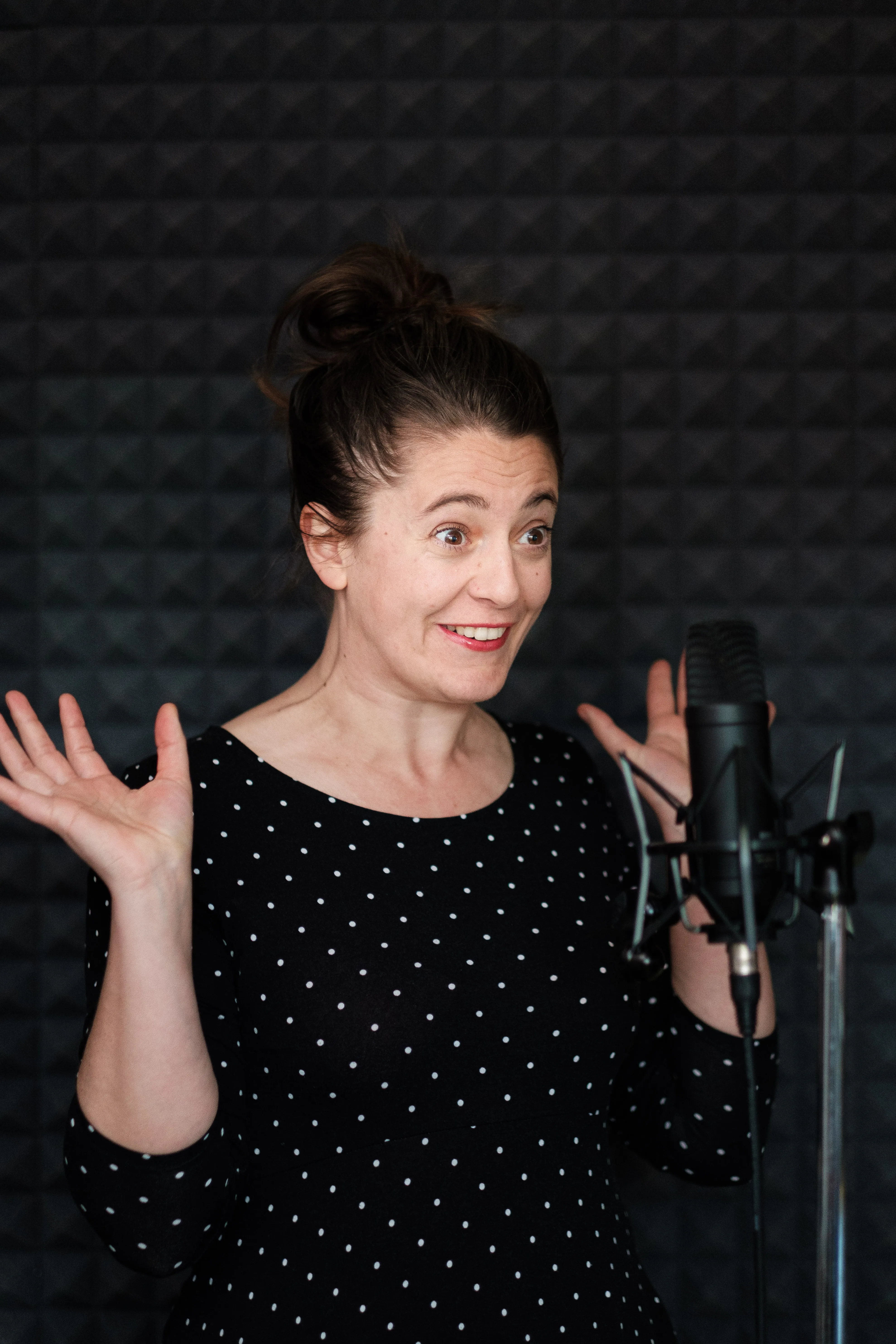 Een stemacteur met een koptelefoon spreekt in een professionele microfoon in een opnamestudio.